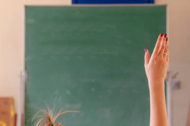 glückliches mädchen hob die hände im klassenzimmer. studentin mit seiner hand zu erhöhen. colledge student im auditorium lektion. die erhobenen hände im klassenzimmer in der schule - confusion mathematics student mathematical symbol stock-fotos und bilder