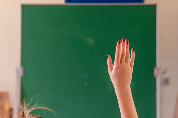 glückliches mädchen hob die hände im klassenzimmer. studentin mit seiner hand zu erhöhen. colledge student im auditorium lektion. die erhobenen hände im klassenzimmer in der schule - confusion mathematics student mathematical symbol stock-fotos und bilder