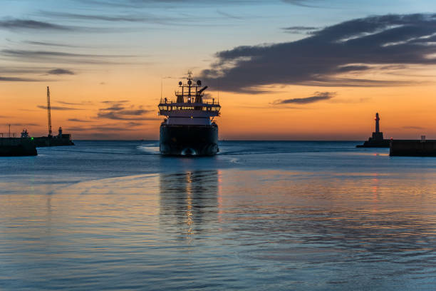 istock Sea wall, lighthouse, sunrise and ship. 844663982