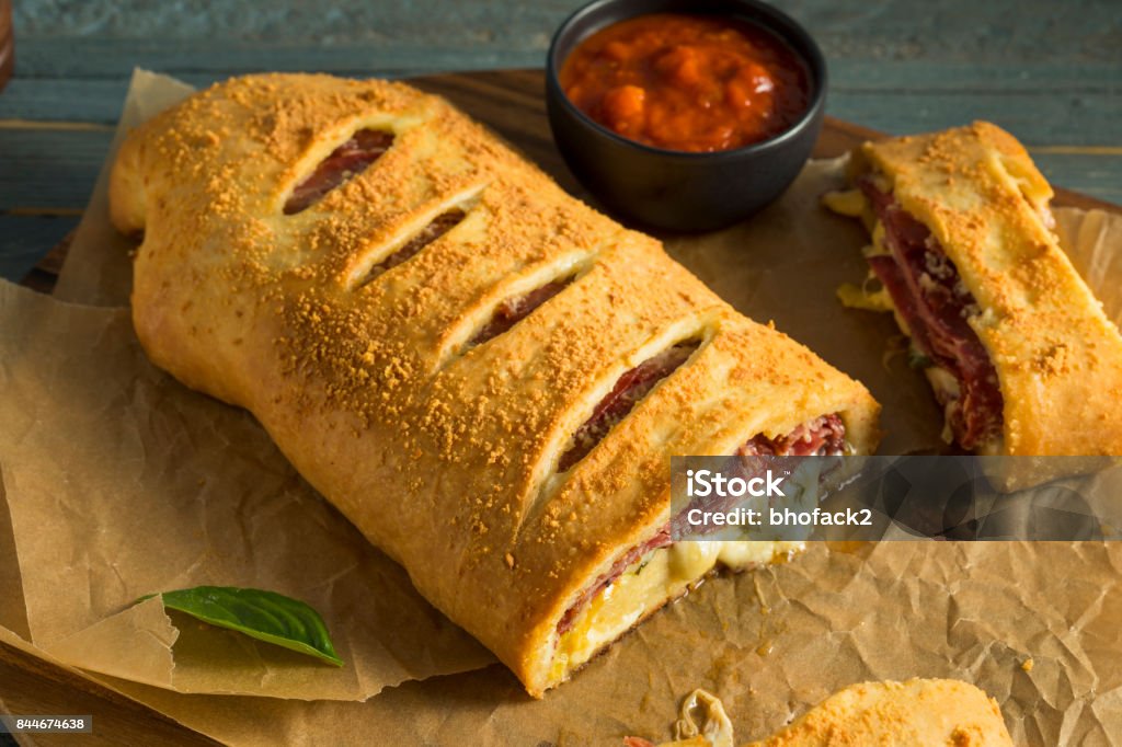 Homemade Cheesy and Meaty Italian Stromboli Homemade Cheesy and Meaty Italian Stromboli with Marinara Sauce Calzone Stock Photo