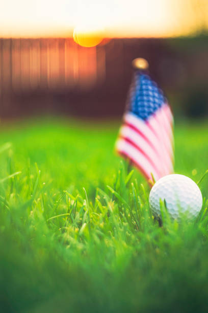 istock Golf ball and American flag in grass with sunlight at dusk 844680028