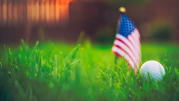 istock Golf ball and American flag in grass with sunlight at dusk 844680104