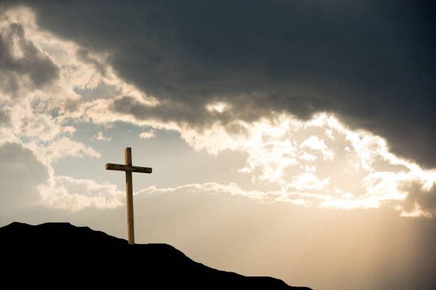 istock Cross on mountain at sunset with sun rays 844694076