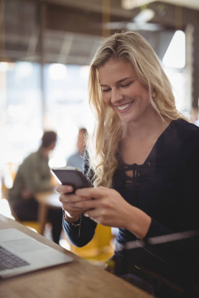 istock Smiling young woman texting through mobile phone at coffee shop 844694726