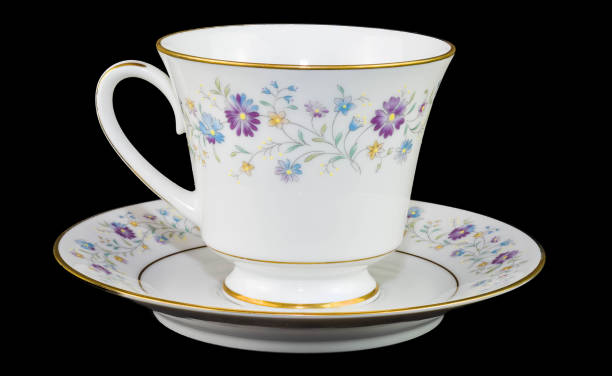 China Tea cup and Saucer isolated on black back ground Teacup and Saucer with a floral print on both the cup and the saucer. Image taken close and is displayed on a black back ground tea cup and saucer stock pictures, royalty-free photos & images