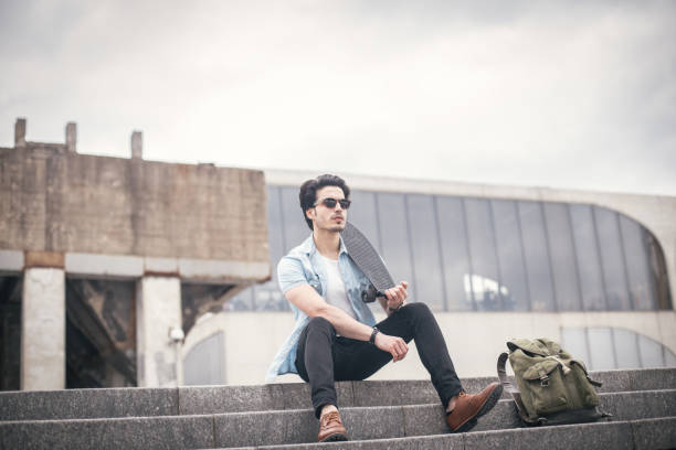 istock Hipster man with penny board sitting on the steps 844746634