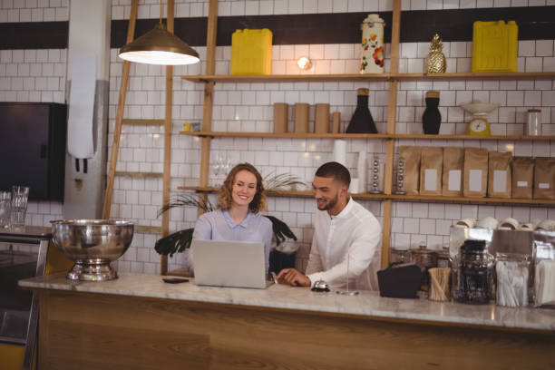istock Young male owner and waitress using laptop while sitting at counter 844768782