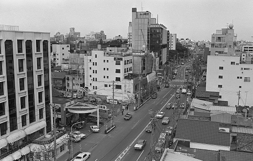 British Hong Kong, China - 1983: A vintage 1980's Fujifilm negative film scan of new office buildings and busy city streets in Hong Kong with pedestrians and cars.