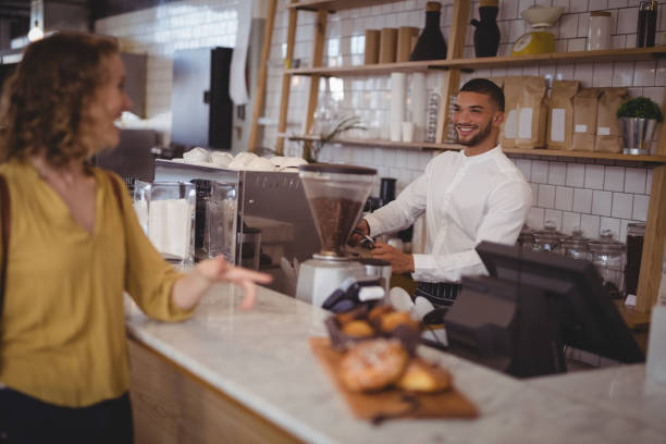 istock Smiling waiter looking at female customer standing at counter 844784542