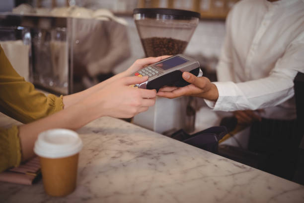 istock High angle view of female customer paying through debit card at counter 844784894