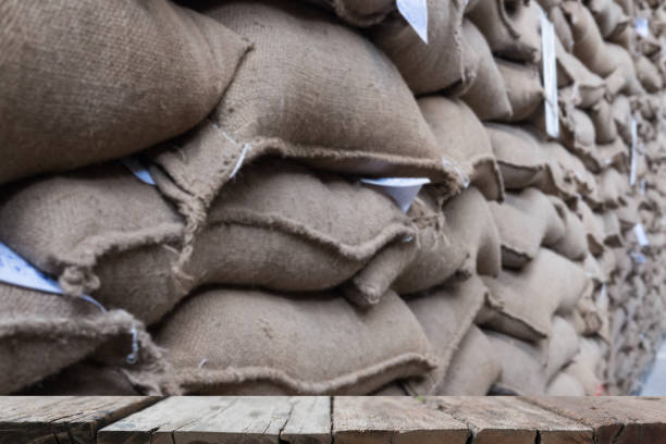 istock hemp sacks containing coffee bean in warehouse. stacked sacks in storehouse with wood table for display your product. 844791300