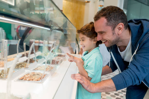 heureux père et fils à la boutique de crème glacée - glacier glace photos et images de collection