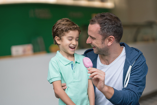 Portrait of a happy father and son eating a popsicle at the ice cream shop - lifestyle concepts