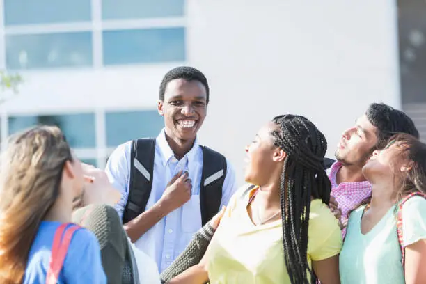 Photo of African-American teenage boy with friends outside school