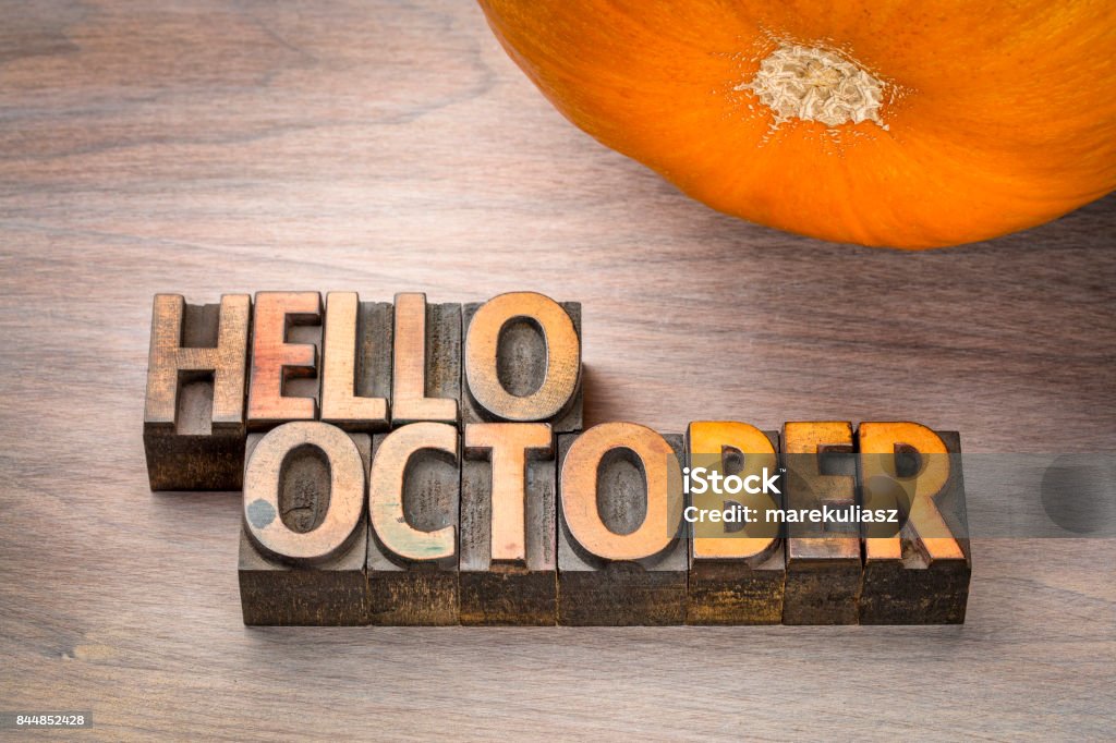 hello October word abstract in wood type hello October greeting card - letterpress wood type blocks against grained wood with a pumpkin October Stock Photo