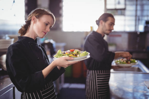 istock Young wait staff holding fresh salad plates while standing in commercial kitchen 844863166