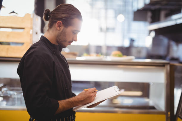 istock Side view of young waiter writing on clipboard 844863674