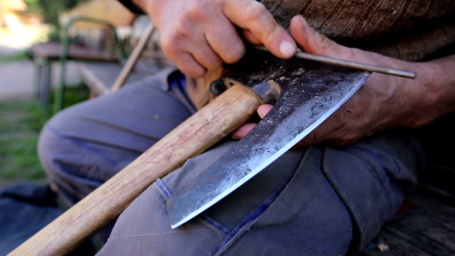 Old man sharpening axe