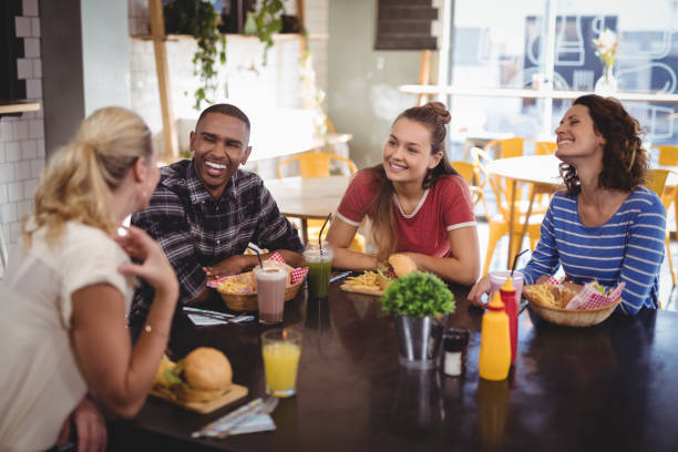 istock Young friends talking while sitting at table with food and drink 844886796