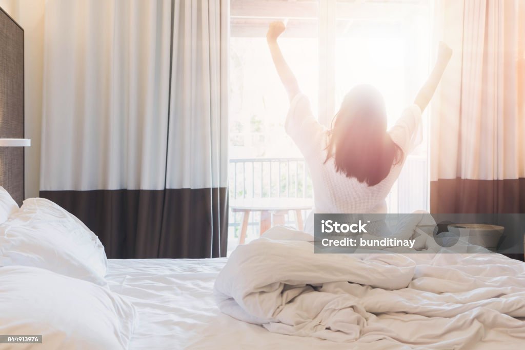 Las mujeres asiáticas se hospeda en una habitación de hotel después de despertar hasta mañana. Abra el telón en la sala mirando a exteriores. Tono vintage. - Foto de stock de Hotel libre de derechos