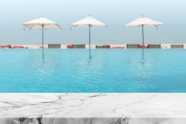 istock White stone marble table top and blurred swimming pool with sea background. - can used for display or montage your products. 844930948