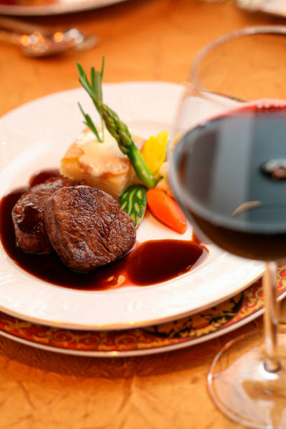Grilled beef filet and glass of wine with bottle on the white fabric. Selective focus. Nobody