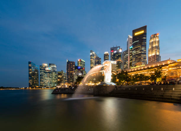 Evening view of the Singapore Merlion statue at Marina Bay against Singapore skyline. The Merlion is a well known marketing icon of Singapore depicted as mythical creature with a lion's head and a body of a fish.