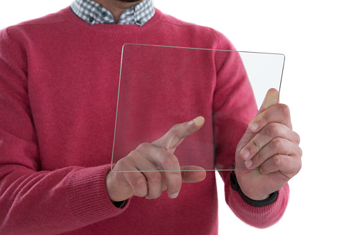 Mid section of man holding glass digital tablet against white background