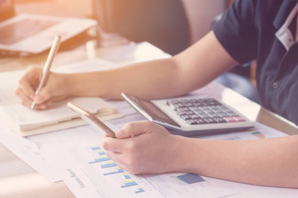istock close up hand woman calculating about cost and using smartphone searching data in office. 845014052