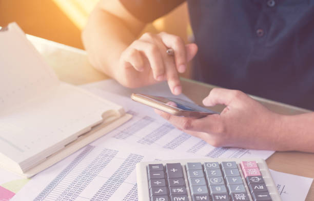 istock close up hand woman calculating about cost and using smartphone searching data in office. 845016586