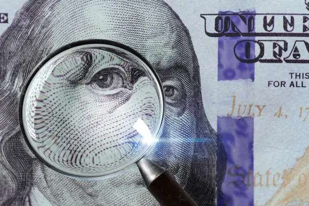 Photo of 100 US Dollar under magnifying glass