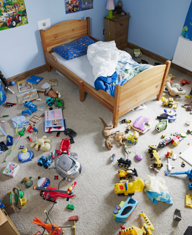 Pathway cleared through toys on floor of boys room to unmade bed.