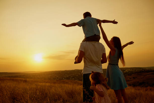 família feliz no campo, ao pôr do sol. - family with two children family park child - fotografias e filmes do acervo