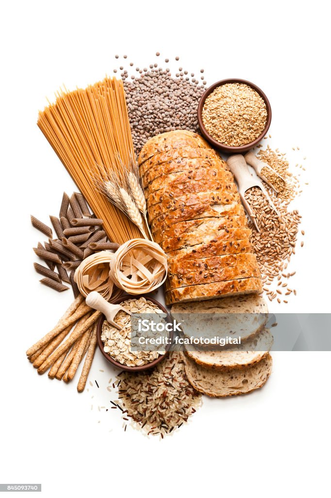 Wholegrain and dietary fiber food on white background Top view of wholegrain and cereal composition shot on white background. This type of food is rich of fiber and is ideal for dieting. The composition includes wholegrain sliced bread, wholegrain pasta, oat flakes, flax seed, brown rice, brown lentils, breadsticks and spelt. Predominant colors are brown and white. DSRL studio photo taken with Canon EOS 5D Mk II and Canon EF 100mm f/2.8L Macro IS USM Bread Stock Photo
