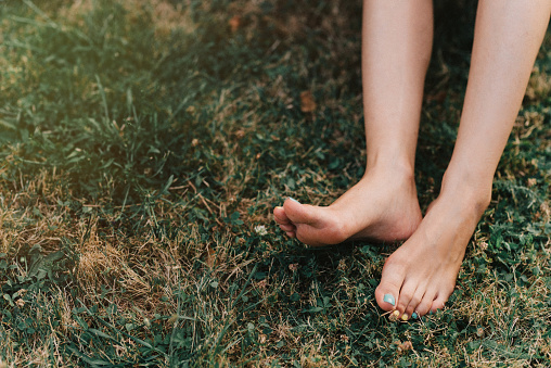 Woman's bare feet on a meadow outdoors.