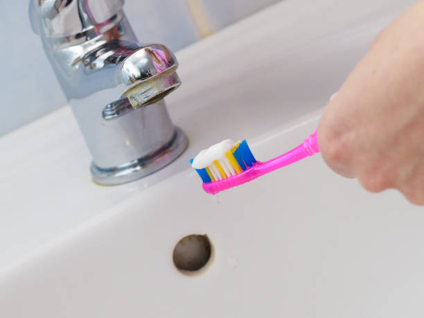 istock Hand holding toothbrush in bathroom 845115068