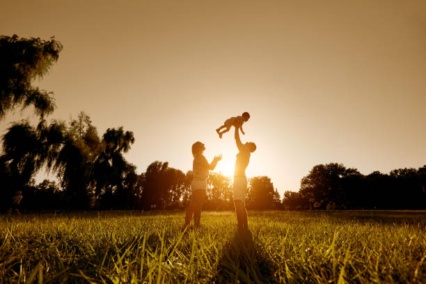 glückliche familie mit einem kind bei sonnenuntergang im park spielen. - nature parks stock-fotos und bilder