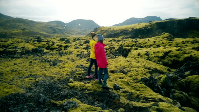 Aerial view of two woman walking on the lava fields in Iceland. Tourists enjoying the landscape, exploring the territory