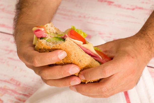 primer plano de un hombre que sostiene un sandwich - sandwich submarine delicatessen salami fotografías e imágenes de stock