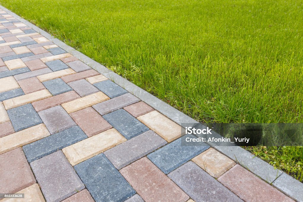 road and lawn divided by a concrete curb Paving Stone Stock Photo