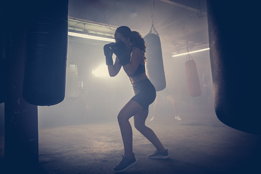 Young woman  boxer with dramatic lighting