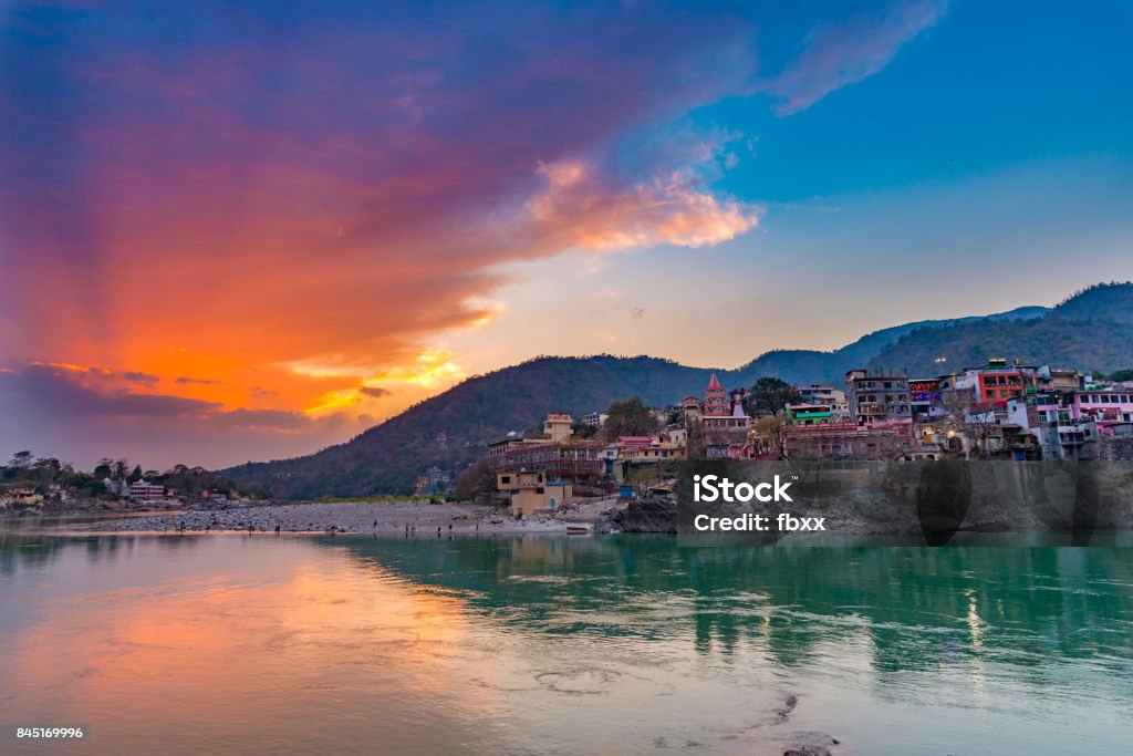 Dusk time at Rishikesh, holy town and travel destination in India. Colorful sky and clouds reflecting over the Ganges River. Rishikesh Stock Photo