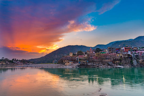 Dusk time at Rishikesh, holy town and travel destination in India. Colorful sky and clouds reflecting over the Ganges River. Dusk time at Rishikesh, holy town and travel destination in India. Colorful sky and clouds reflecting over the Ganges River. ghat photos stock pictures, royalty-free photos & images