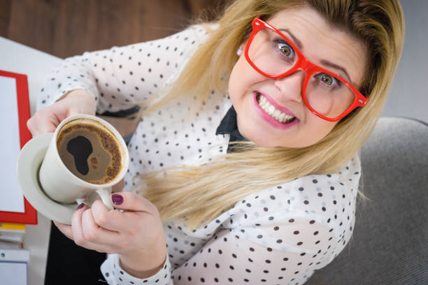 Happy woman at office drinking hot coffee or tea enjoying her break time during work. Job relax.
