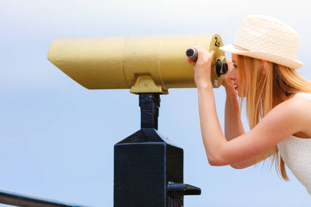 istock Woman tourist with sun hat looking through telescope 845180138