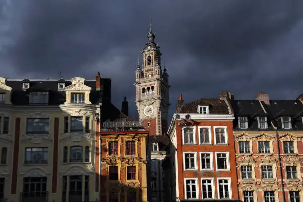 Clock tower of the stock exchange building in Lille, France against dark rainclouds