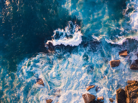Aerial view of waves and some rocks.