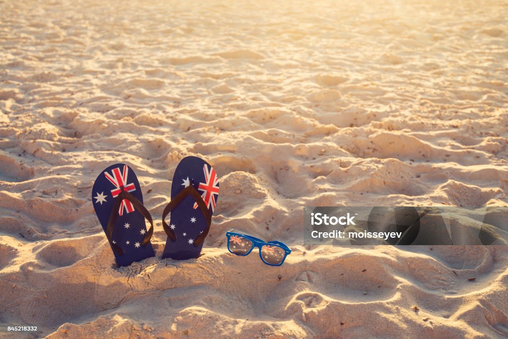 Thongs and sunglasses on beach sand Thongs and sunglasses in sand on a beach, Australia day concept Australia Day Stock Photo