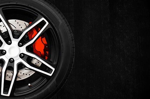Alloy wheels of racing car with metal brake discs and red caliper.
