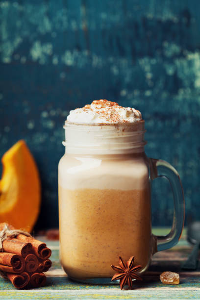 istock Cozy breakfast. Pumpkin spiced latte or coffee in cup decorated cinnamon on teal vintage table. Autumn, fall or winter beverage. 845271182